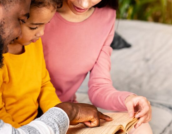 International parents reading a book with their bilingual child at home