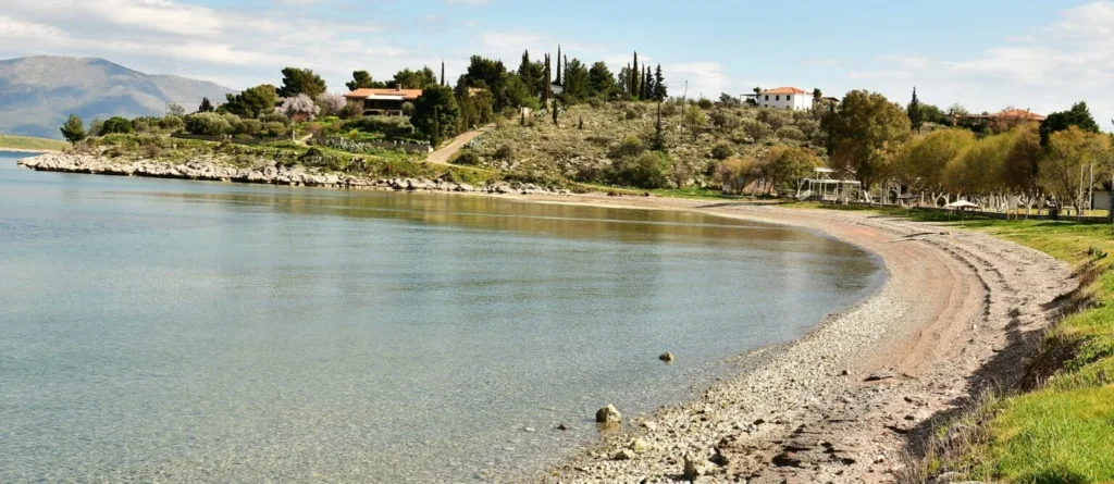 Kalafatis Beach in Galaxidi, with a curved sand and pebble shore and calm water