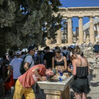 Visitors drink water beneath the Parthenon during extreme heat in Athens