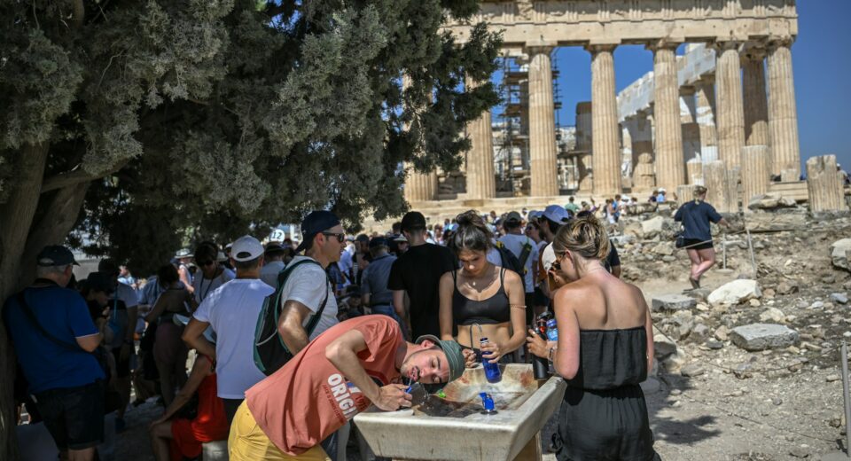 Visitors drink water beneath the Parthenon during extreme heat in Athens