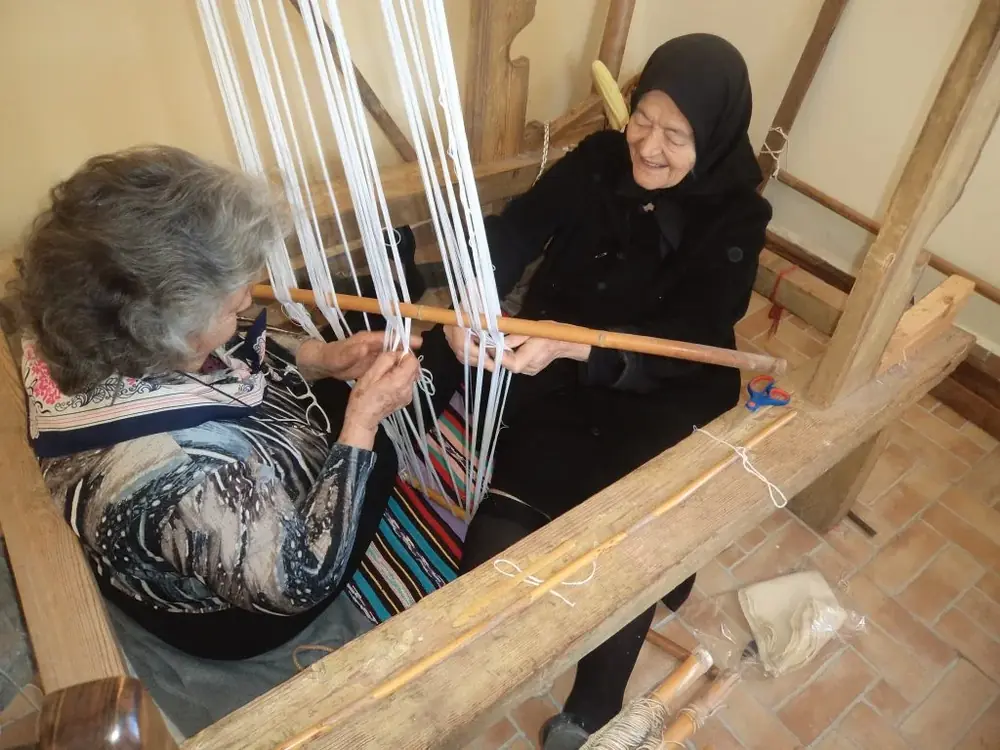 Two women practising traditional weaving on a wooden loom in Asterousia, Crete.