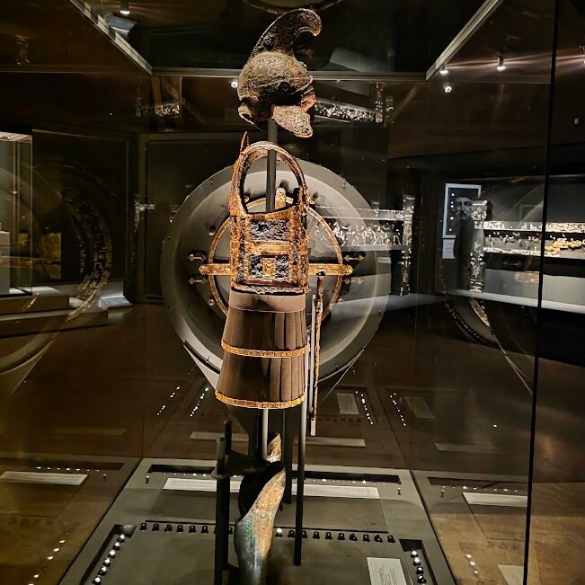 Gold-decorated panoply of Philip II, including iron-and-gold cuirass with lion-head fastenings, embossed iron helmet with Athena, and sword with ivory-adorned sheath. Museum of the Royal Tombs of Aigai, Expats Athens, Expats Greece, Xpat.gr