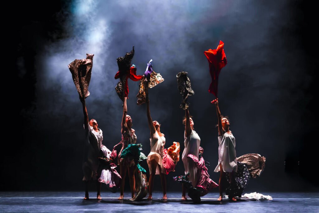 Dancers holding colourful garments on stage in Maldonne by Leïla Ka.