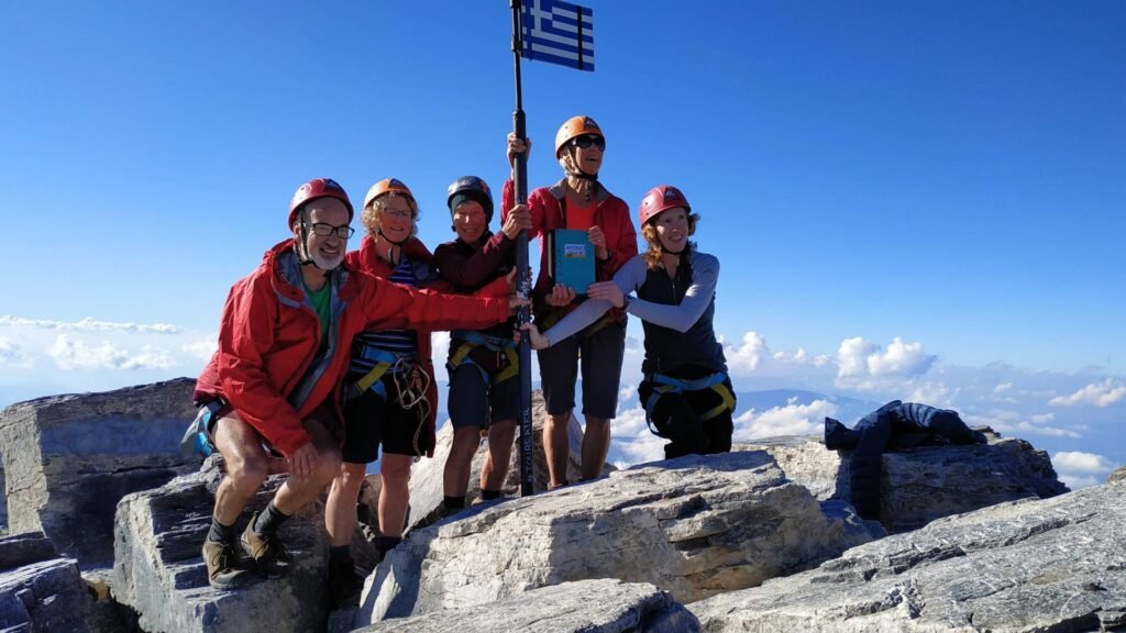 Group of hikers at the summit area of Mount Olympus with the Greek flag during an Unlimited Adrenaline experience featured on Xpat.gr.