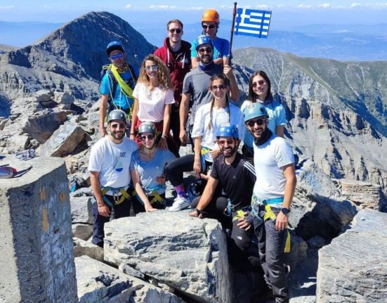 Group of hikers at the summit area of Mount Olympus with the Greek flag during an Unlimited Adrenaline mountain adventure featured on Xpat.gr.