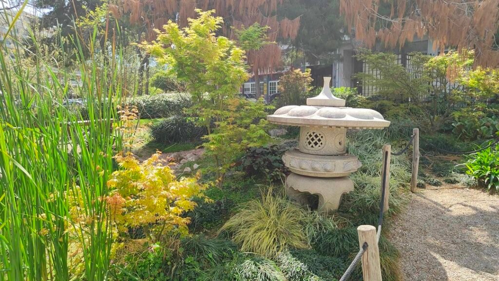 Stone lantern among plants and garden paths at the Japanese Park of Athens.