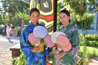 Two visitors holding fans during a previous Natsu Matsuri celebration at the Japanese Park of Athens.
