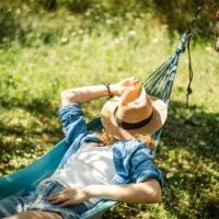 Woman resting in a hammock outdoors, enjoying a peaceful afternoon nap in the shade.