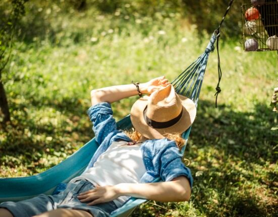 Woman resting in a hammock outdoors, enjoying a peaceful afternoon nap in the shade.