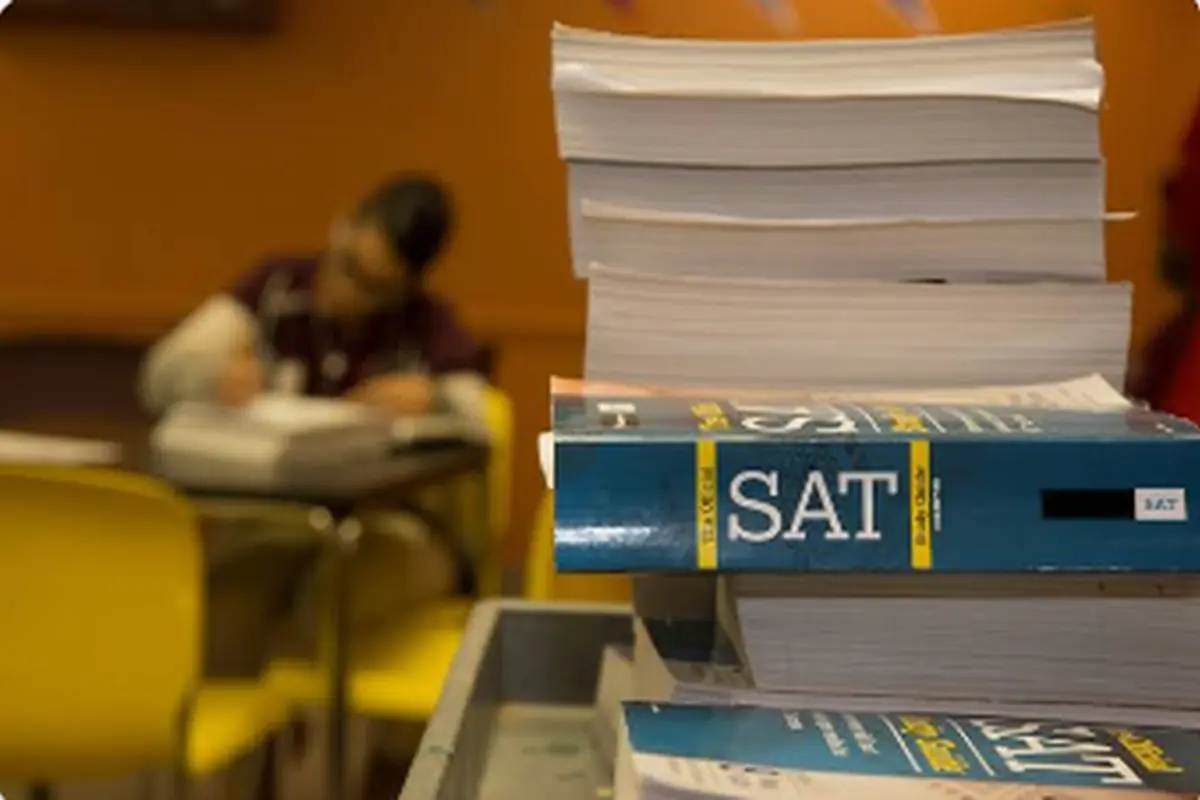 SAT preparation books in the foreground as a student studies in a classroom