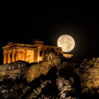 Full moon rising behind the illuminated Acropolis of Athens at night