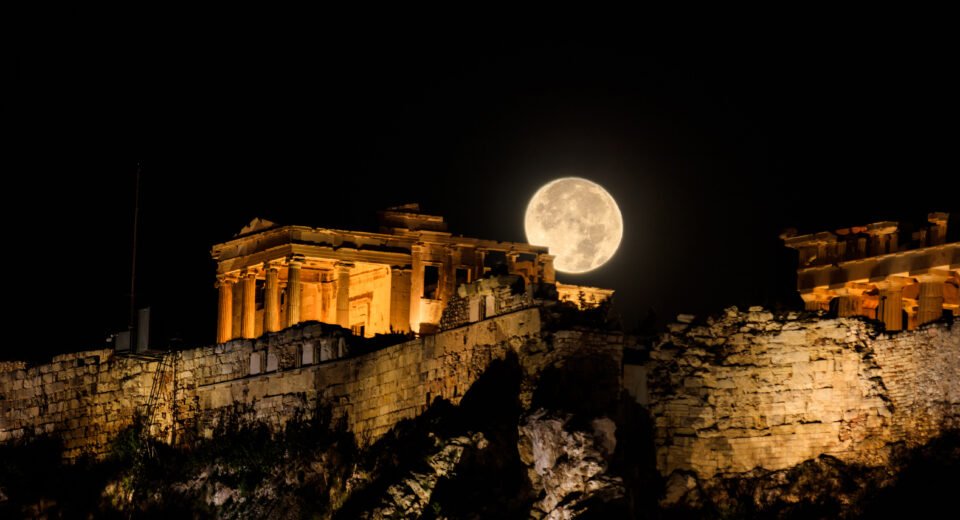 Full moon rising behind the illuminated Acropolis of Athens at night