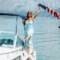 American tourist holding a US flag while enjoying a boat trip in Greece