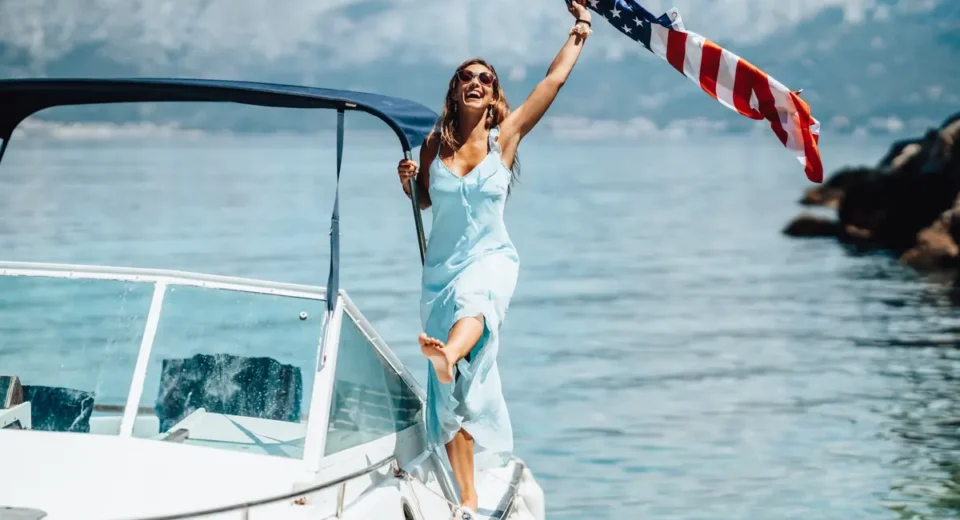 American tourist holding a US flag while enjoying a boat trip in Greece