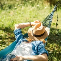 Woman resting in a hammock during a quiet summer afternoon, illustrating the tradition of the Greek siesta.