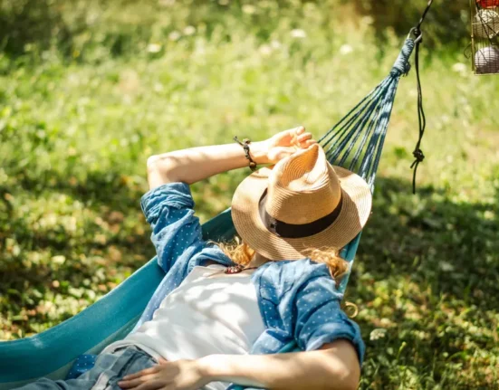 Woman resting in a hammock during a quiet summer afternoon, illustrating the tradition of the Greek siesta.