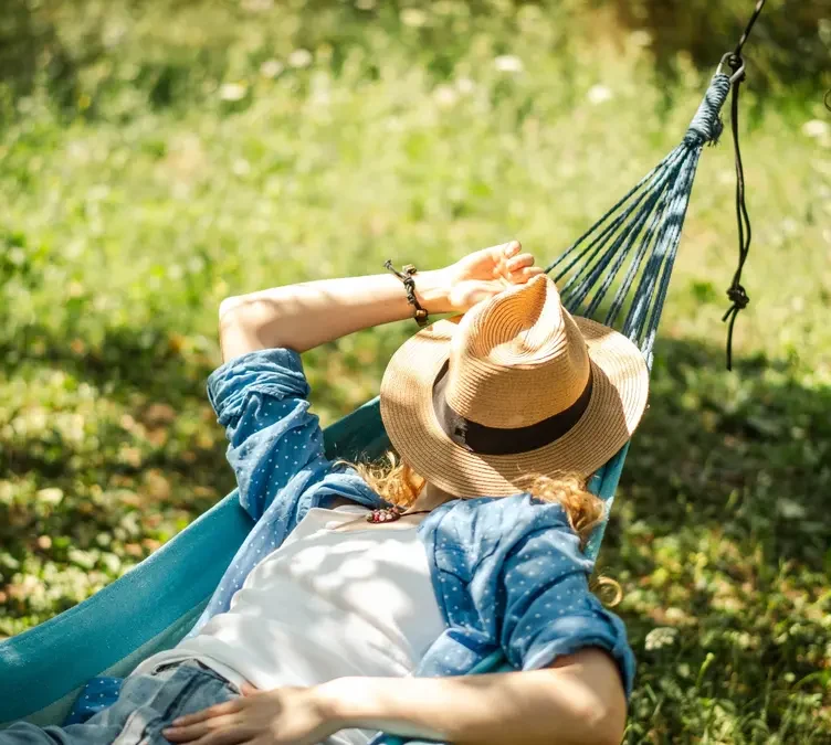 Woman resting in a hammock during a quiet summer afternoon, illustrating the tradition of the Greek siesta.