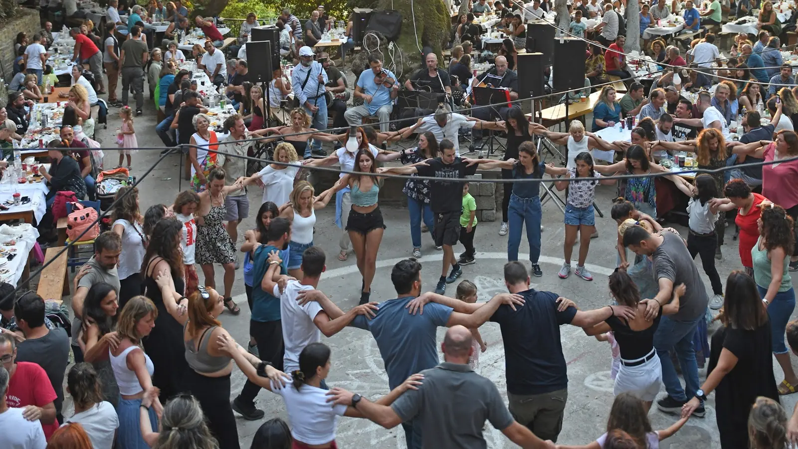 People dancing in a circle at a traditional village panigiri in Ikaria, Greece
