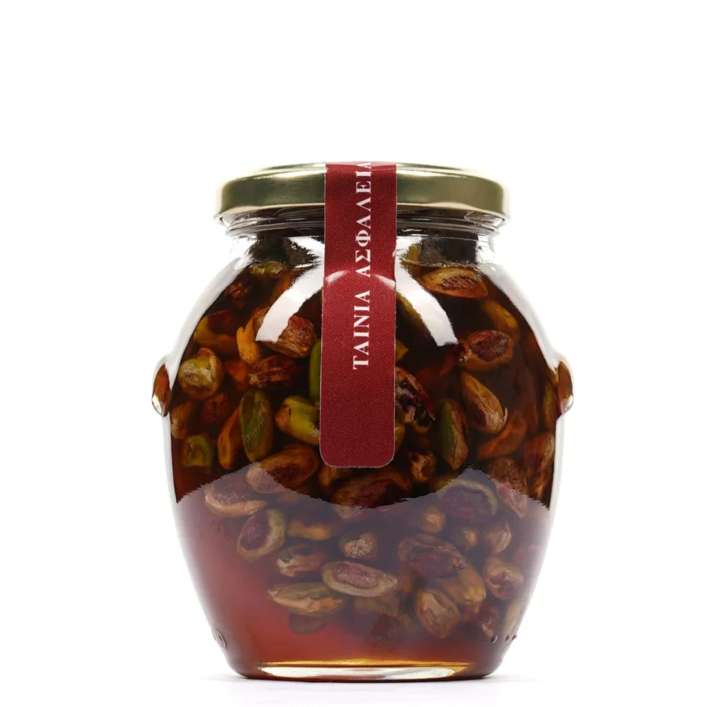 Glass jar of honey containing whole pistachio kernels.
