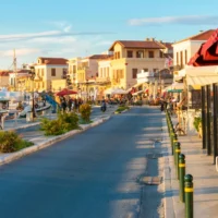Aegina Town waterfront with moored boats, seafront buildings and outdoor cafés.