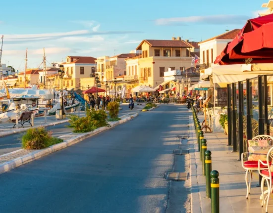 Aegina Town waterfront with moored boats, seafront buildings and outdoor cafés.