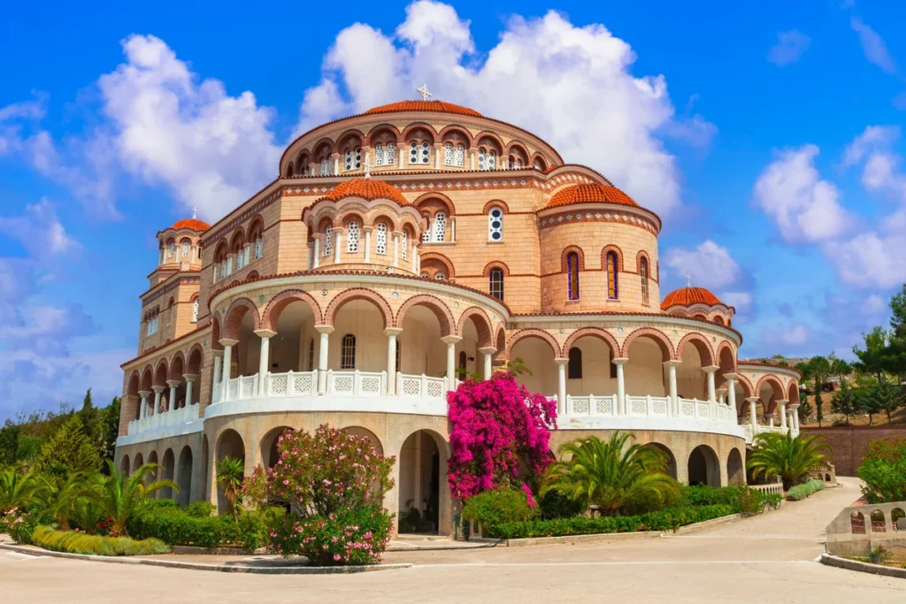 Agios Nektarios church with red-tiled domes, arched galleries and flowering bougainvillea.