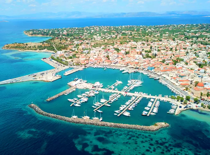 Aerial view of Aegina Town, showing its harbour, yacht marina and red-roofed buildings beside the turquoise sea.