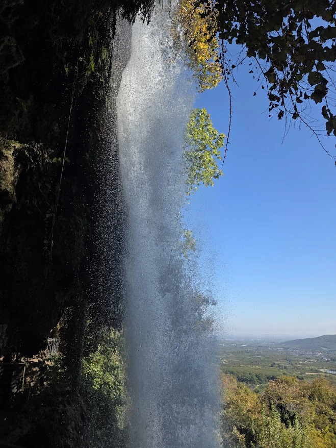 View through Karanos Waterfall towards the Macedonian plain from the walkway behind the falls