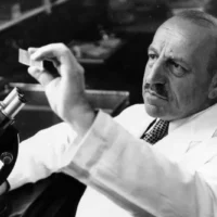 Georgios Papanikolaou examining a microscope slide in his laboratory.