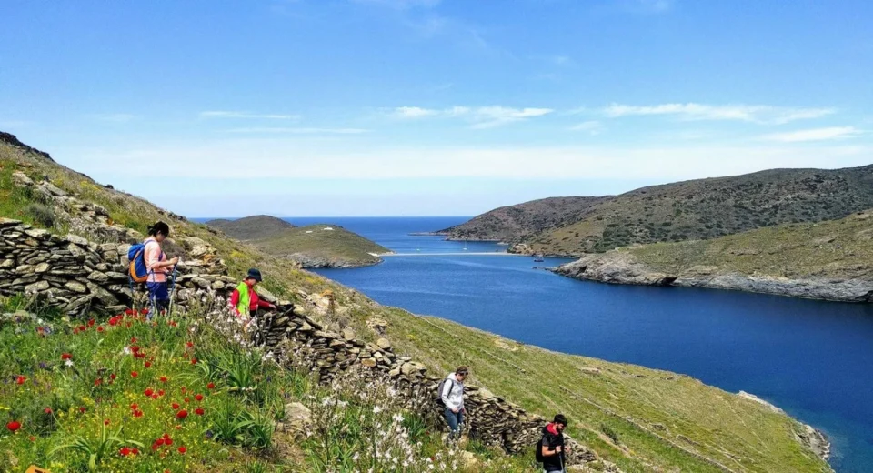 Hikers walking along a hillside trail above the Aegean Sea on Kythnos island, Greece.