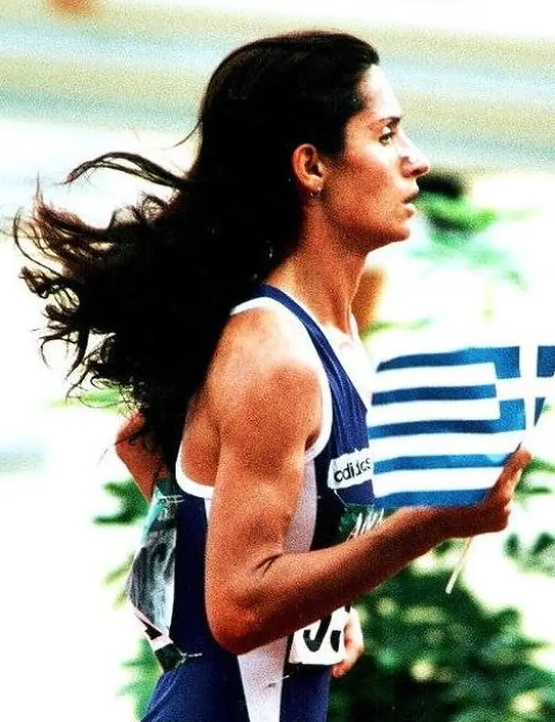 Greek marathon runner Maria Polyzou running while carrying the Greek flag.