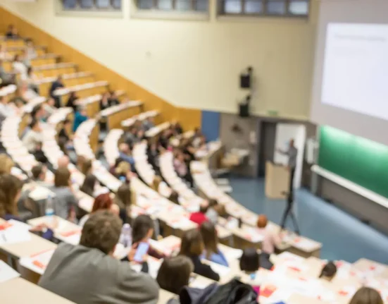 Students attending a university lecture in a large auditorium