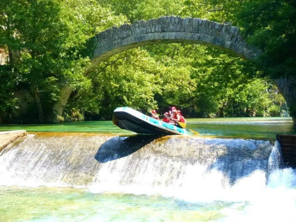 Raft passing beneath a traditional stone bridge in the Pindus region