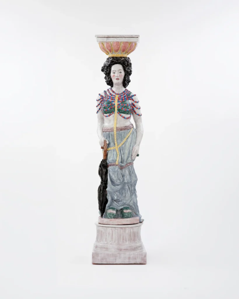 Rachel Feinstein’s Petra, a dark-haired majolica caryatid supporting an architectural capital.