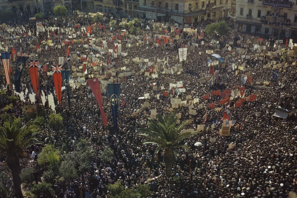 Crowds carrying Greek and Allied flags gather in central Athens on 18 October 1944 to welcome the returning Greek government.
