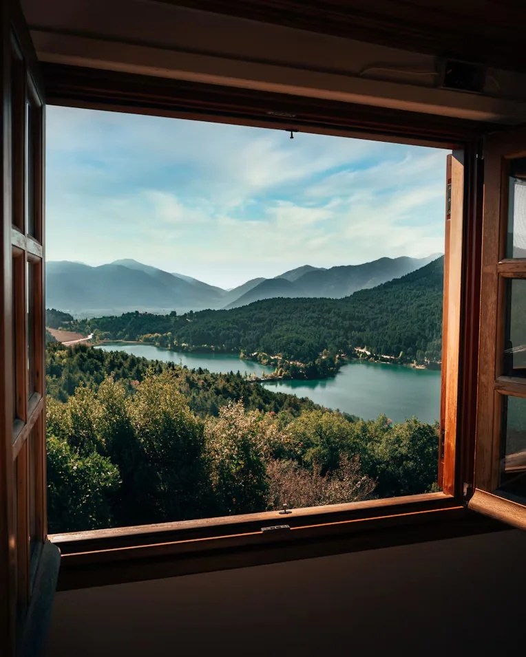 Lake Doxa framed by a wooden window at the Monastery of Agios Georgios